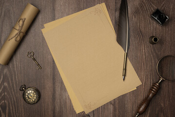 Vintage quill pen and empty old blank paper sheet with old accessories on wooden background from...