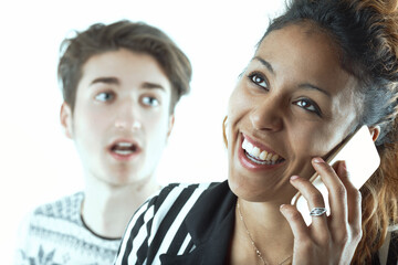 Woman smiles on phone, man appears jealous