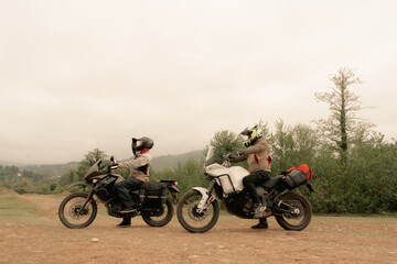 Bikers friends in motorcycle trip on adventure enduro motorcycles in mountains driving off-road