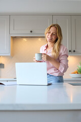 Smiling Woman Working From Home In Kitchen Using Laptop