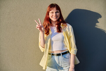 Young smiling red-haired hipster female with facial piercing looking at camera outdoor