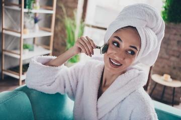 Photo portrait of lovely young lady apply roller massager face wrapped towel dressed bath robe...