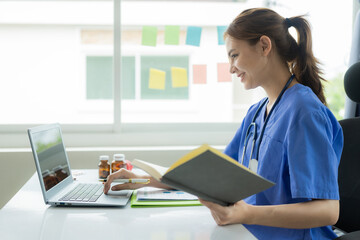 Beautiful young female doctor working with laptop Read electronic medical records Doctors provide...
