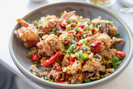 A delicious plate of crispy golden brown fried soft shell crab tossed in a flavorful chili garlic sauce with scallions and bell peppers.