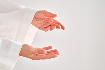 Female hands in a white robe stretch to the right.