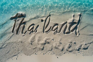 Fototapeta premium The word Thailand carved in the sand, washed by shimmering aqua waves