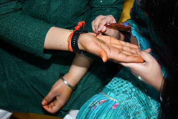People standing with hands touching, holding out an object together in a Mehndi Ceremony