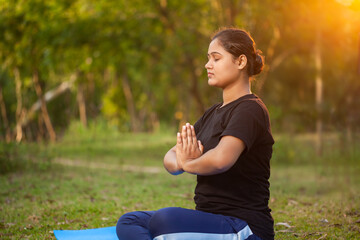 young women concentrating on Pranamasana or prayer pose yoga while sitting on an exercise mat at...