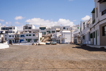 Typical white houses of the village of Caleta de Caballo. Dirt street and boats on the ground. Lanzarote, Canary Islands, Spain