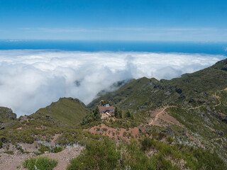 View from Pico Ruivo peak towards the refuge Casa de Abrigo do Pico Ruivo. Green mountains, misty...