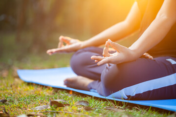 women doing apana mudra yoga at outdoor during morning sunrise, cropped view