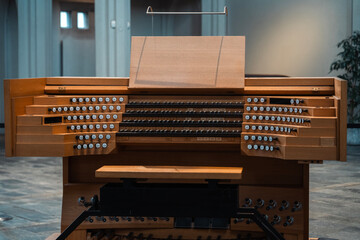 Large organ keyboard with many stops. Wooden musical instrument in a large cathedral. Sacred music,...