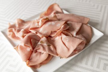 Thinly sliced sausage, ham on a white plate