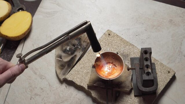 Jeweler melts silver in a small crucible, powdering it with borax. Goldsmith working on his workshop.