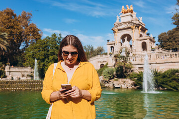 Young female tourist with phone visiting Ciutadella Park in Barcelona. Concept of travel, tourism...