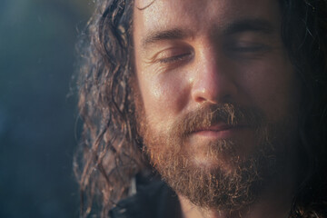 Portrait of man wet from humidity. Hiker with long hair and beard near a waterfall. Happiness,...