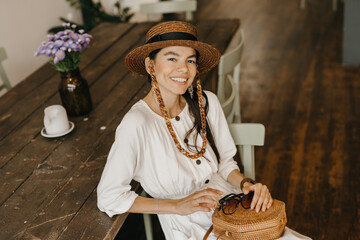 beautiful woman sitting in cafe on vacation dressed in white summer fashion dress