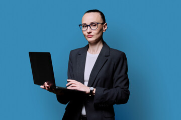 Middle-aged business confident woman using laptop on blue background
