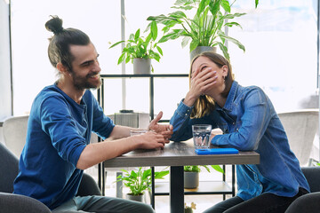 Laughing cheerful young couple sitting together in cafe