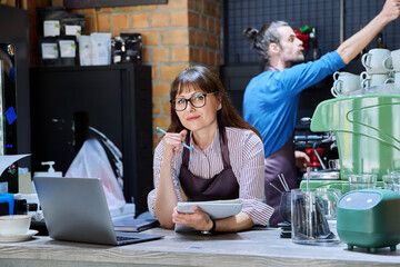 Colleagues, partners, man and woman behind counter in coffee shop