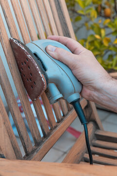 Man Refinishing Wooden Chair with Sander