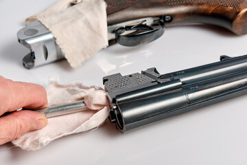 a shooter carefully wipes the chamber of his shotgun with a rag