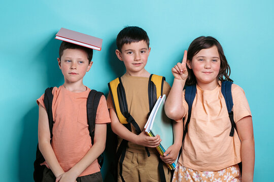 Three school kids with backpacks and books