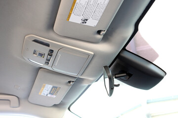 Close up interior view of the car roof or ceiling light panel. Car ceiling lamp, interior's details in modern car. Car headliner. Sun visor auto. Rearview mirror. 
