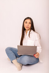 A young woman in white shirt with a laptop sits on white background.Work online