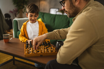 Father and son play chess together at home