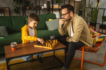 Father and son play chess together at home