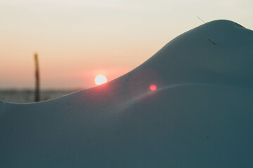 Frosty winter sunset in the field. Beautiful sunset in the snowy desert. Ice and sun.