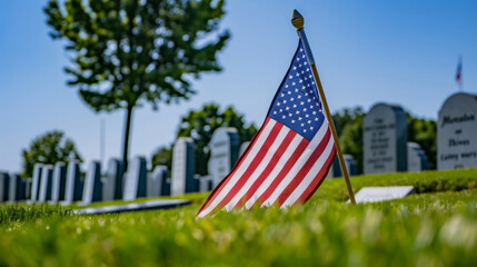 An American flag laying in the green grass of a cemetery, symbolizing honor and remembrance on Memorial Day.