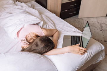 Lady working remotely while lying in bed talking on a video call.
