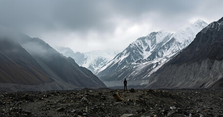 A man stands confidently in the center of a vast mountain range, surrounded by rugged peaks and valleys.