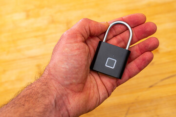 Black biometric padlock with fingerprint secure in hand. Black biometric padlock with fingerprint...