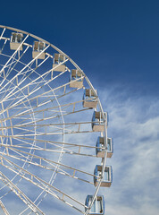 A majestic Ferris wheel stands tall against a cloudy blue sky. Amusement Park. Vertical photo.