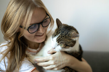Happy young 30s woman with cat in bed at home. In cold weather, Pet friendly concept. Stray kitten...