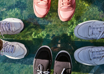 A top-down view of people's feet standing on a glass bridge.