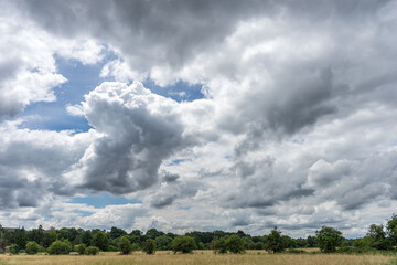 Huge sky full of fluffy clouds in English landscape with low horizon. Optimistic.