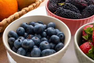Closeup view of blueberries, strawberries and black mulberries in bowls