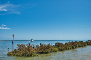 Entrance to the harbor of Port Hedland, Western Australia, with buoys, tugboat and mangrove-covered breakwater