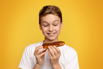 A delighted boy about to enjoy a tasty chocolate eclair.