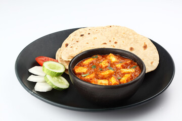 Paneer curry recipe made using cottage cheese, served in a bowl. selective focus Delhi, Rajasthan India. Indian veg curry on blue background. side dish Roti, Chapati, naan.