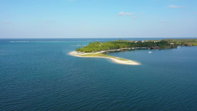 Drone overhead view of the beach of Constance Belle Mare Plage in Mauritius, with palm trees, umbrellas and a beautiful turquoise sea with transparent water. Luxury 5 star hotel in Mauritius.