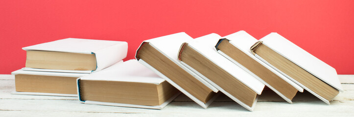 Books, hardback colorful books on wooden table. Red background. Back to school. Copy space for...