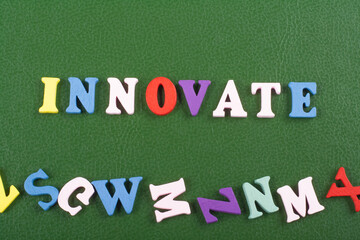 INNOVATE word on green background composed from colorful abc alphabet block wooden letters, copy...