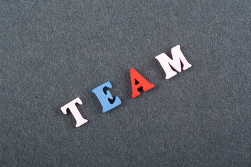 TEAM word on black board background composed from colorful abc alphabet block wooden letters, copy...