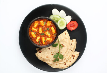 Paneer curry recipe made using cottage cheese, served in a bowl. selective focus Delhi, Rajasthan India. Top view Indian veg curry on blue background. side dish Roti, Chapati, naan.