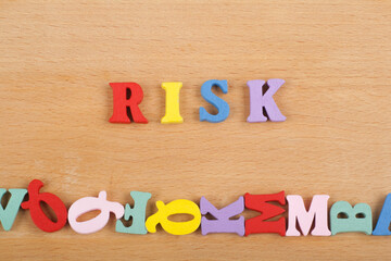 RISK word on wooden background composed from colorful abc alphabet block wooden letters, copy space for ad text. Learning english concept.